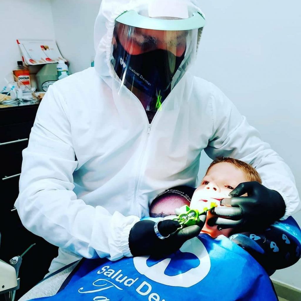 Odontólogo de Salud Dental Táchira atendiendo a un niño con el babero de la clínica