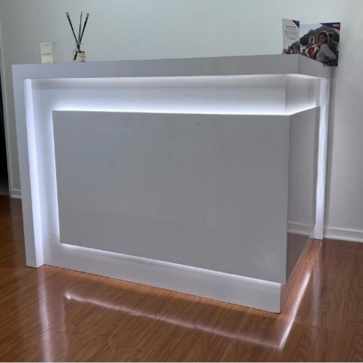 Mesón de recepción blanco con iluminación LED perimetral, fabricado por Sobel Muebles