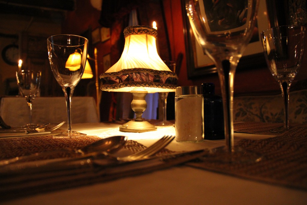 Detalle de mesa con copas de vino, lámpara de aceite y velas encendidas