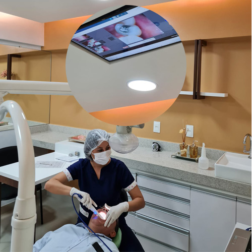 Atendimento odontológico em consultório da Sorriso & Cia, com equipe utilizando equipamento de imagem