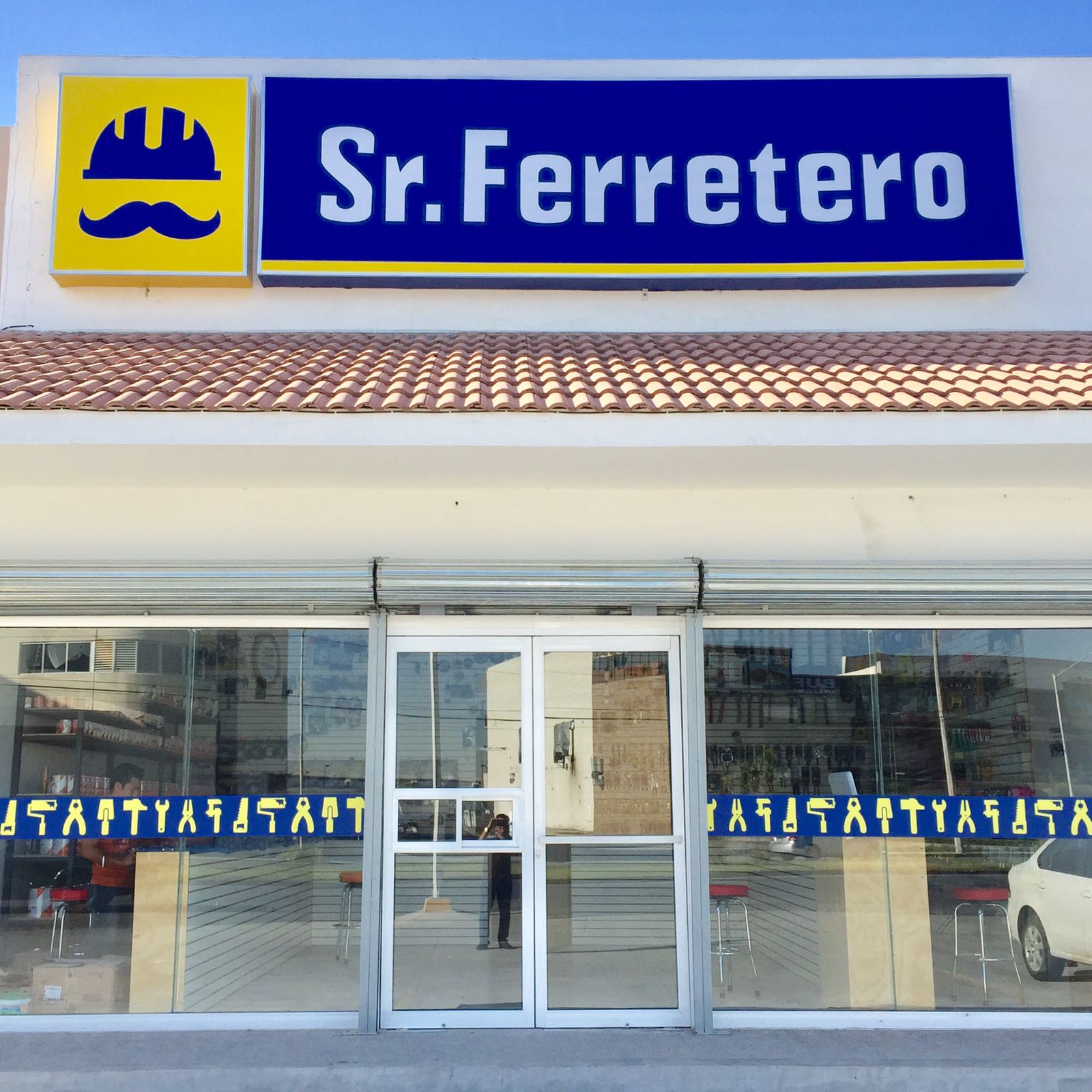 Fachada de Sr. Ferretero con techo de teja y cristales amplios