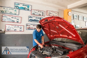 Técnico de Tecniardila revisando el motor de un carro rojo dentro del taller en Bucaramanga
