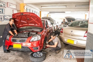 Dos técnicos de Tecniardila trabajando en un carro rojo dentro del taller en Bucaramanga