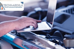Técnico de Tecniardila usando un computador portátil para diagnóstico electrónico bajo el capó de un carro