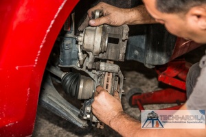 Técnico de Tecniardila trabajando en la mangueta y el freno de un carro rojo