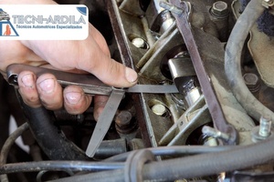 Técnico de Tecniardila reparando el motor de un vehículo con guantes de trabajo