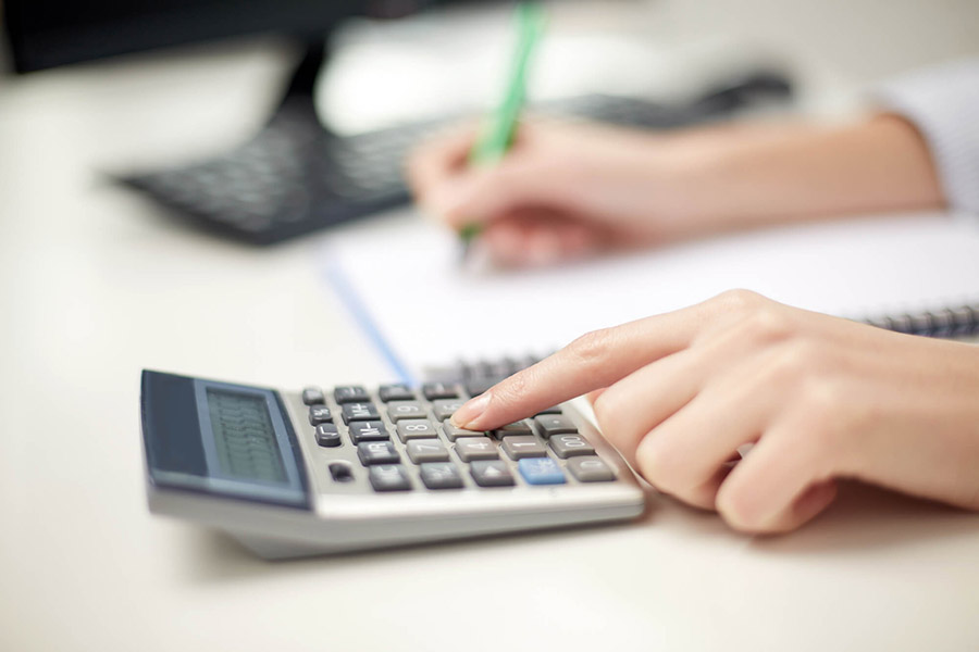 Persona usando una calculadora y anotando en una libreta, trabajo de oficina