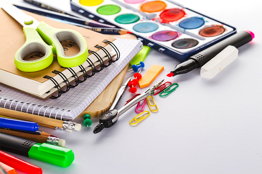 Útiles escolares: cuadernos, tijeras, acuarelas, lápices y marcadores sobre un escritorio