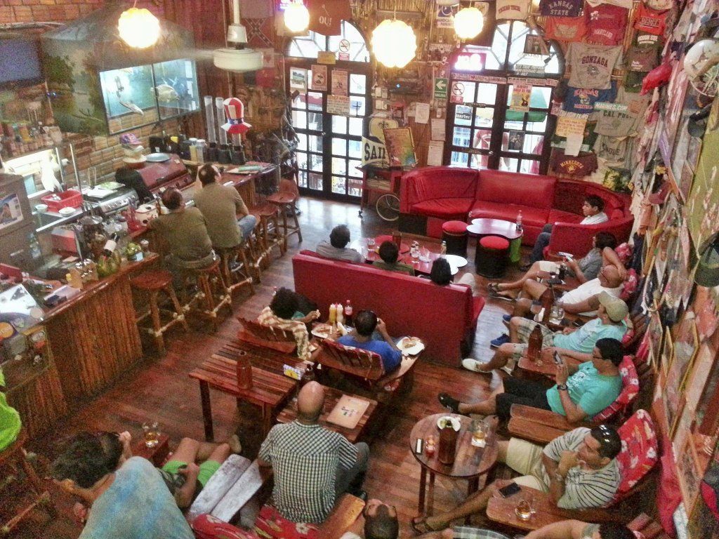 Interior de The Yellow Rose of Texas visto desde el segundo piso, con sillones rojos, barra y mesas llenas de comensales
