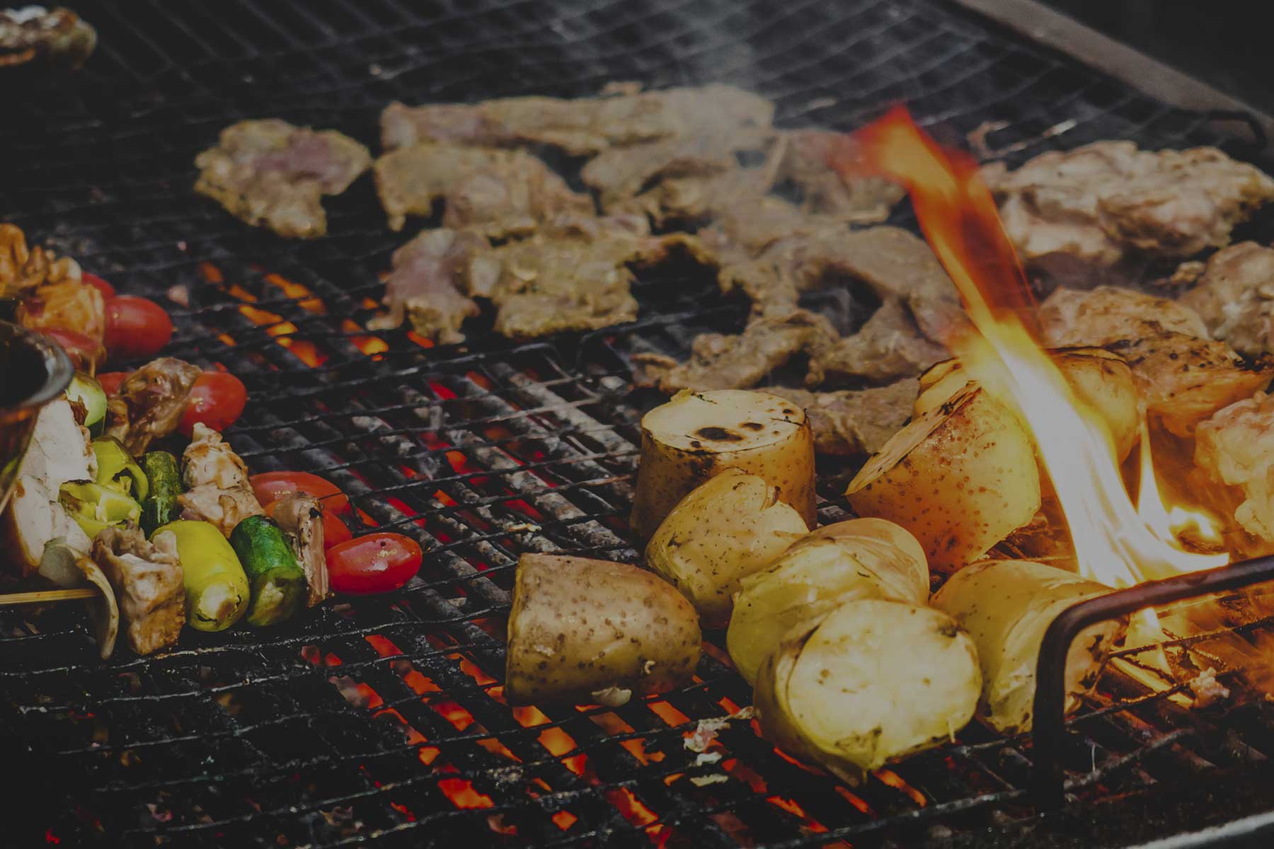 Parrilla al carbón de The Yellow Rose of Texas con carnes y papas asadas sobre las brasas