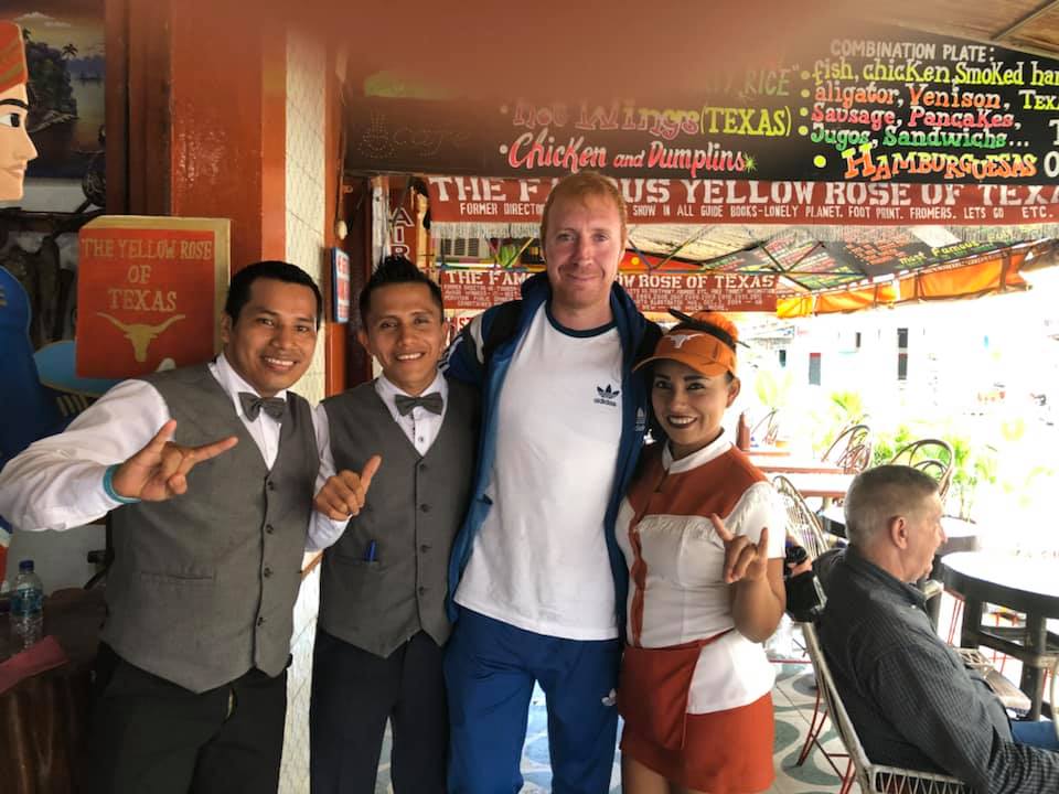 Personal del restaurante junto a una comensal con gorra de Texas Longhorns en The Yellow Rose of Texas